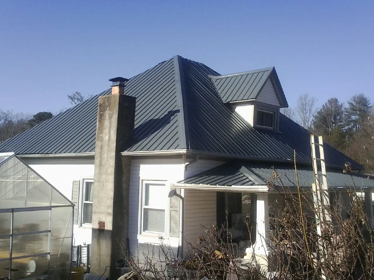 Dark blue standing seam metal roof on a white farmhouse with dormer — Slate & Tile Roof Repair by Roofing Brothers in Sparland