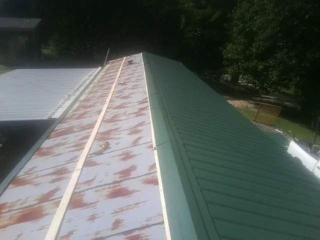 Old rusted panels beside newly installed green metal roofing — Wind Damage Roof Repair by Roofing Brothers in Sparland