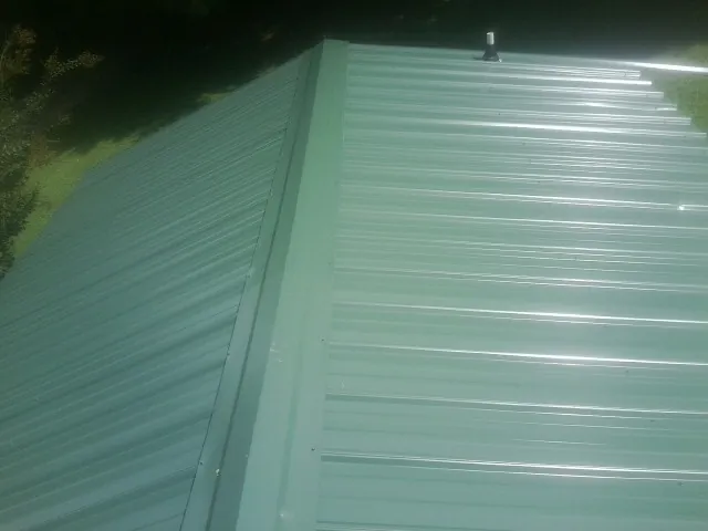 New green metal panels meeting at the ridge of a roof — Flat Roof Repair work by our crew in Sparland