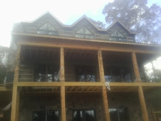 Dormers and porch framing on a large log home under construction — Roof Coating work by our crew in Sparland