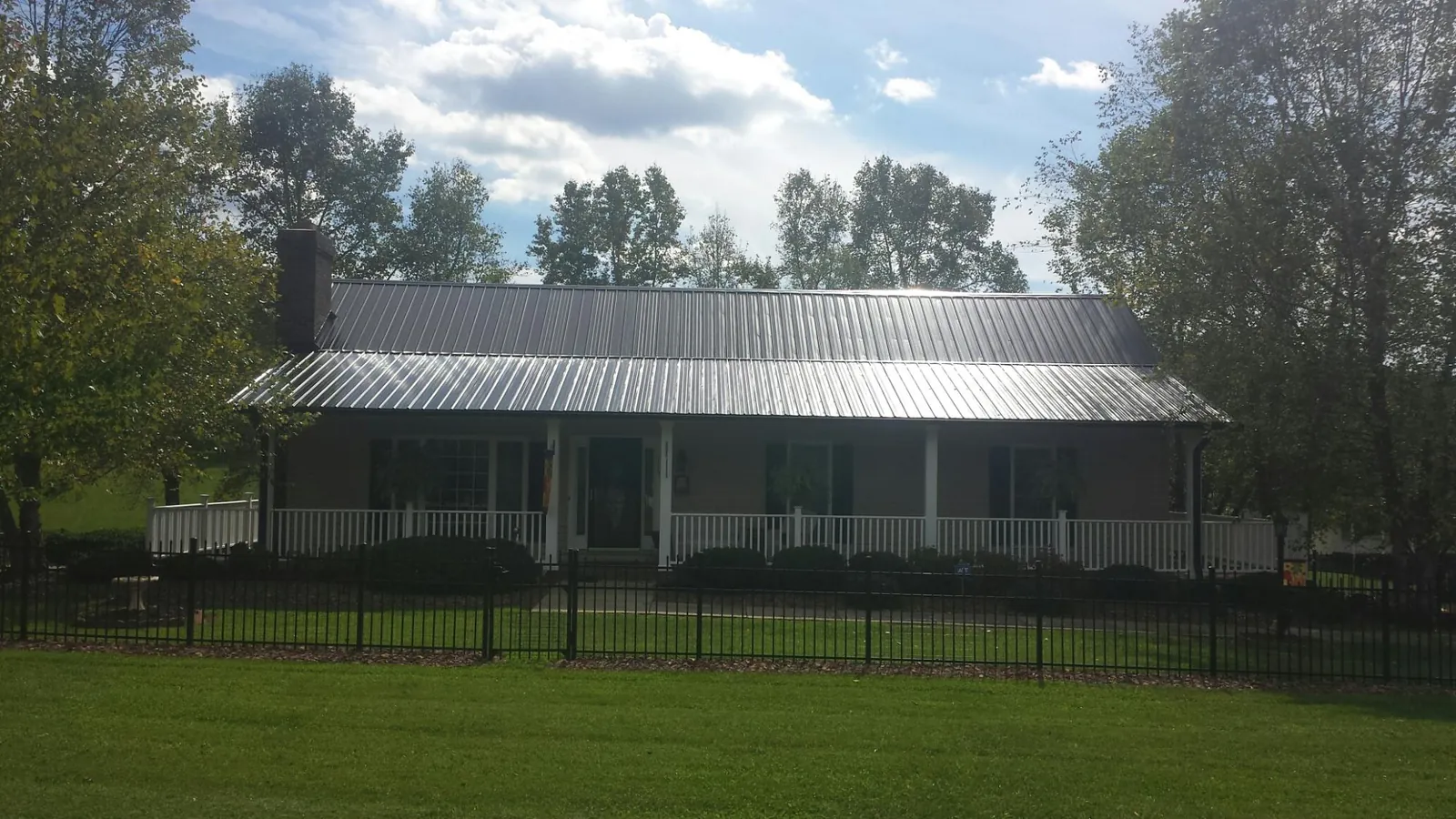 Gray metal roof on a brick ranch with a full width front porch — Gutter Guard Installation work by our crew in Sparland