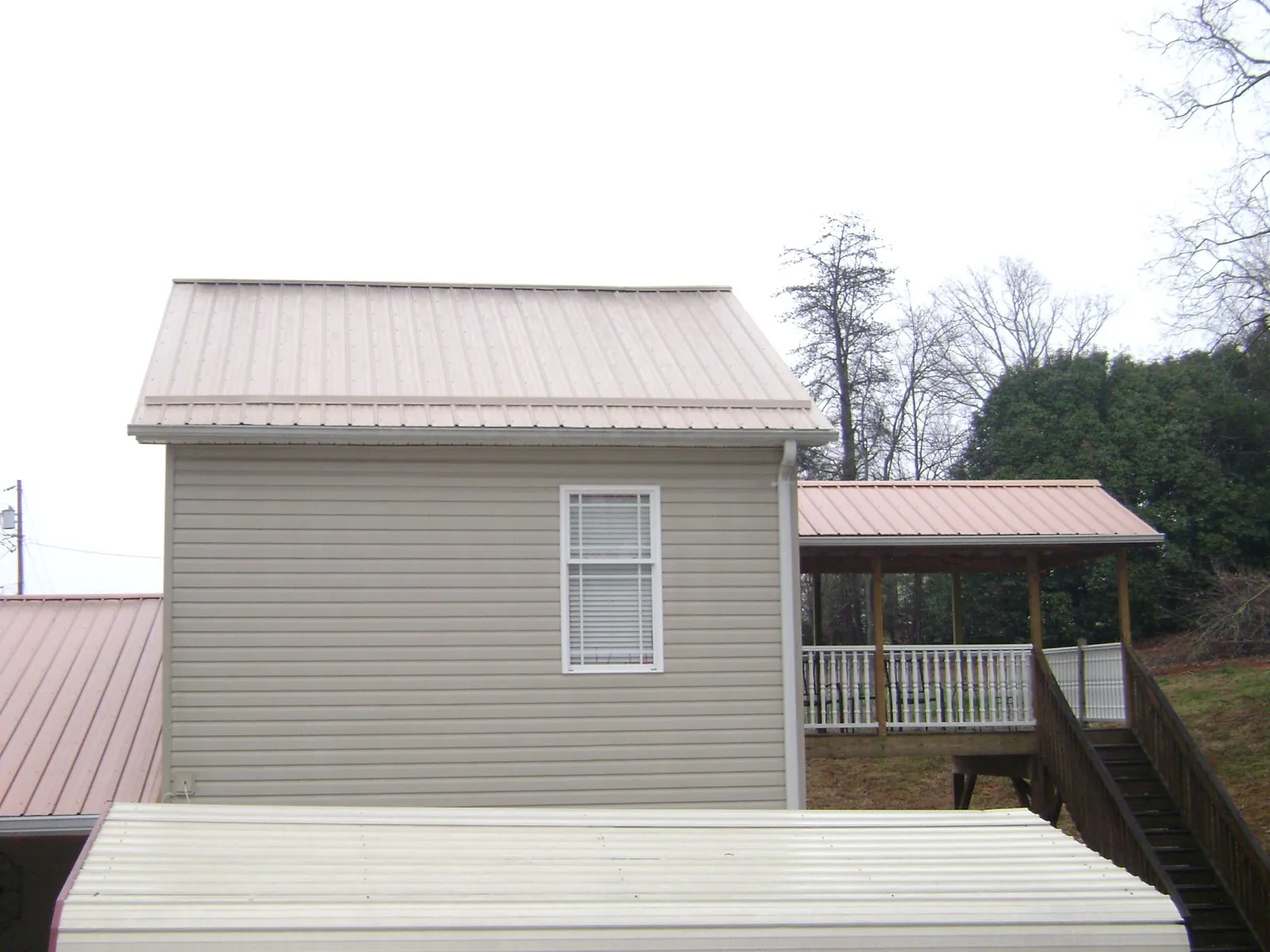 Tan metal roofs on a two story addition and attached porch, from a Roof Replacement job in Sparland