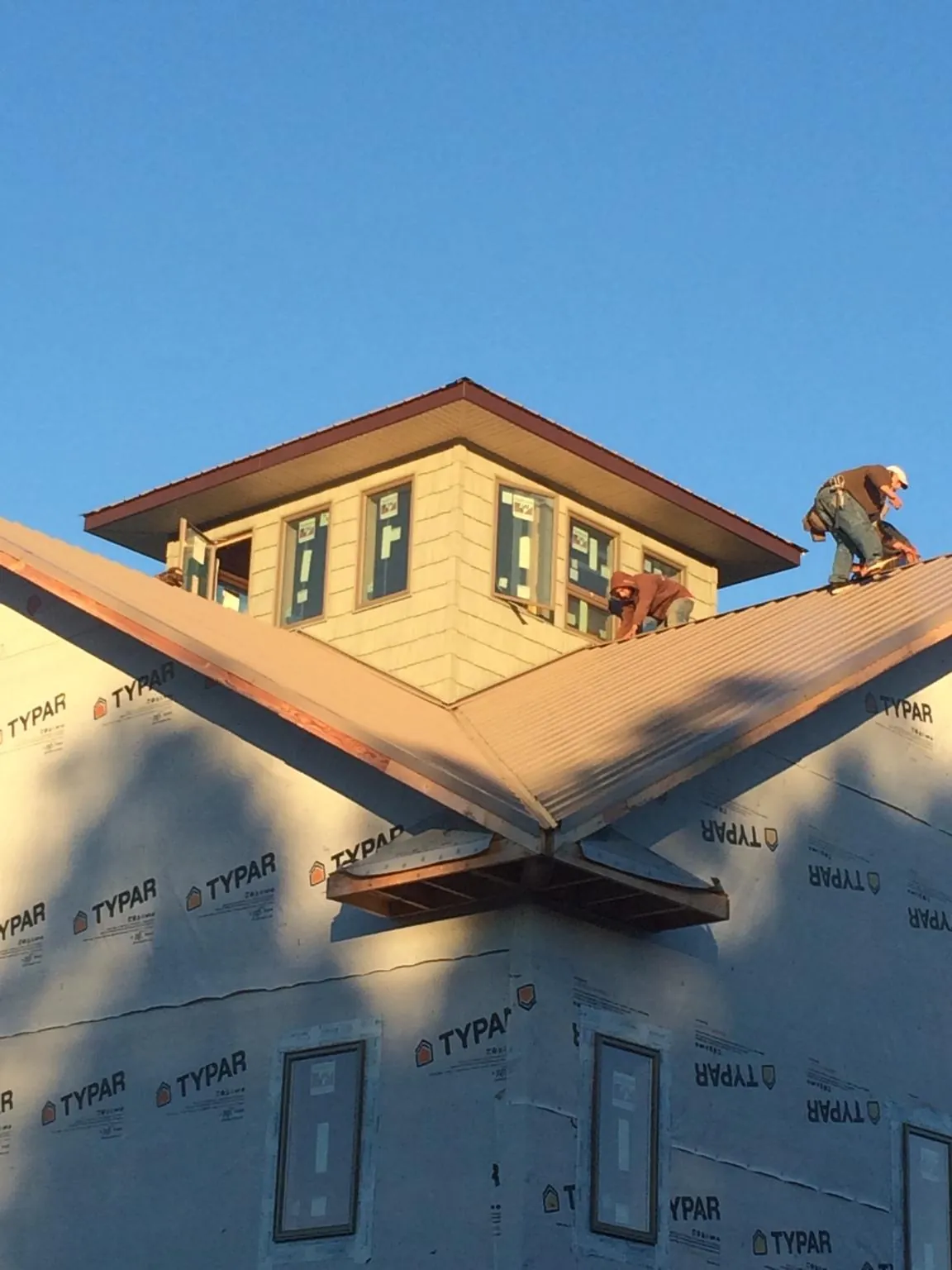 Roofers working around a rooftop cupola on a new metal roof at sunset — Roof Waterproofing in Sparland by Roofing Brothers
